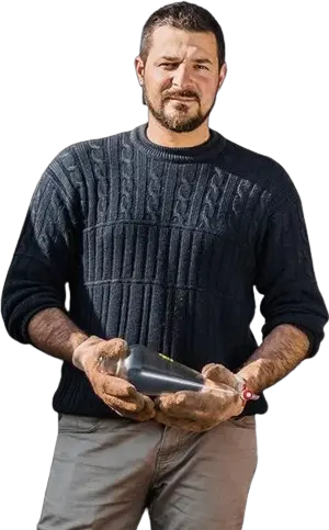 Benjamin, le distillateur au travail, tenant une flasque en verre dans ses mains gantées.